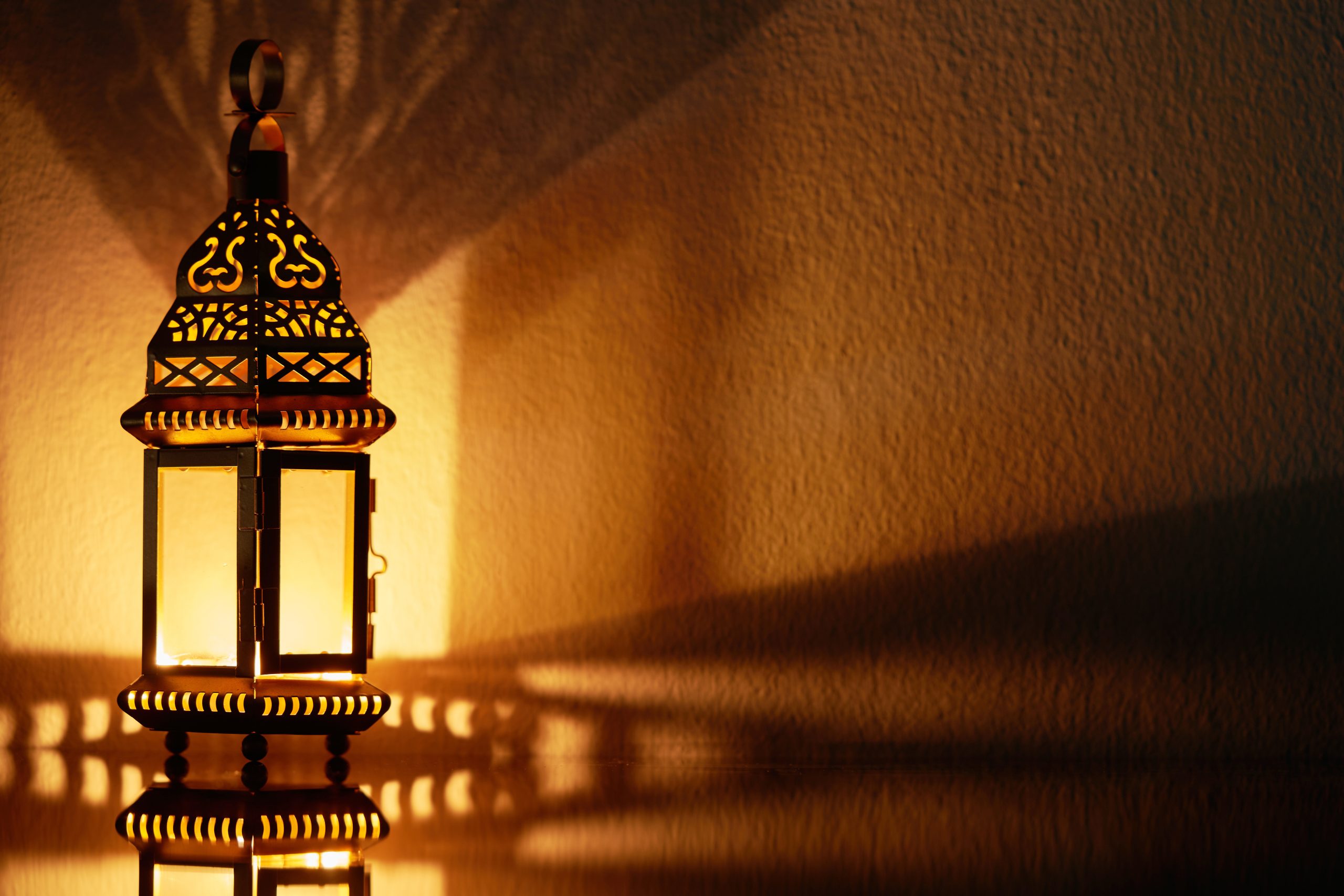 Ornamental Arabic lantern with burning candle glowing at night.